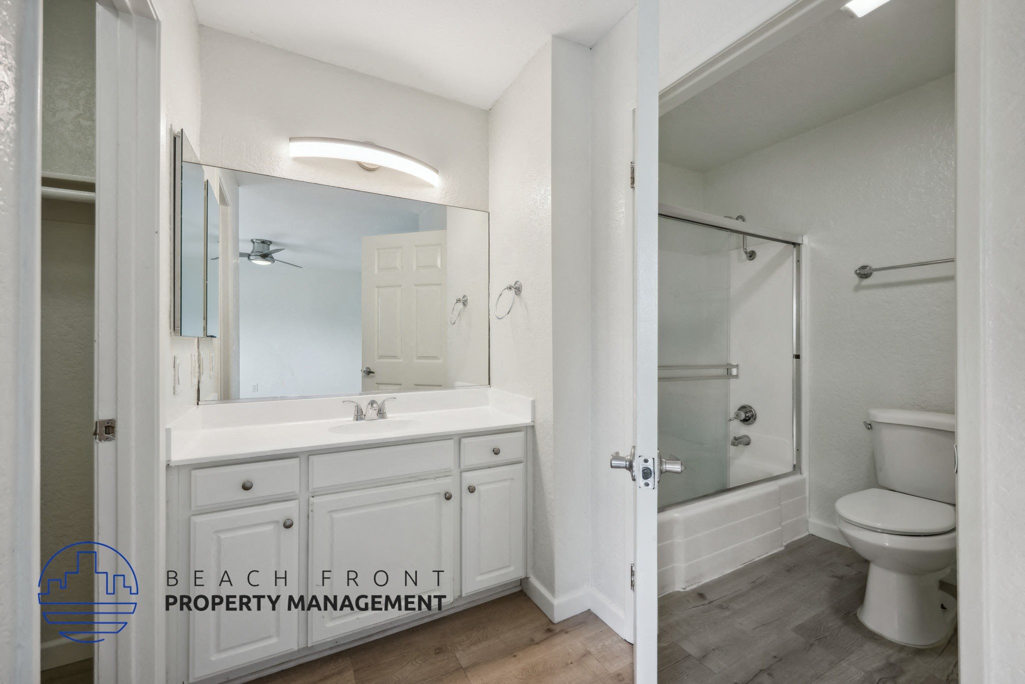 A bathroom with a white toilet and a white sink with a mirror above it.